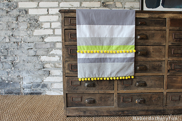 This is a fun and easy tutorial for a table runner with pom pom on the ends. Also a perfect stash buster.  Get more info at HaberdasheryFun and how to sew a colorful pom pom table runner.